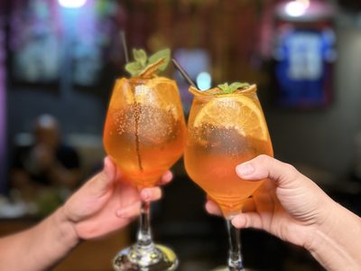 Dos cócteles de naranja brindando en el bar